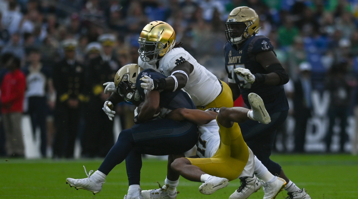 Notre Dame safety Ramon Henderson (11) and Irish linebacker Marist Liufau (8) tackle Navy fullback Daba Fofana.